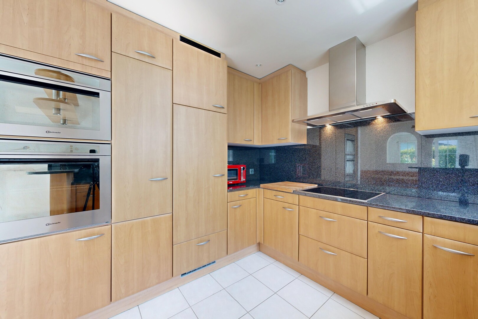 cuisine avec armoires marron clair, light brown cabinets, four, hotte, et light floor