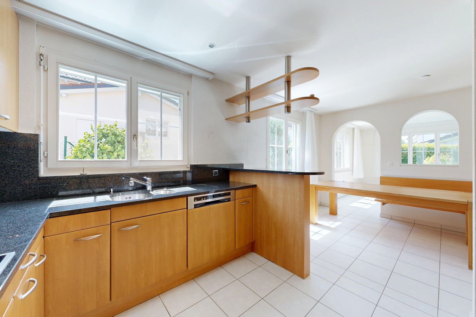 cuisine avec dark countertops, light floor, two heights countertops, medium brown cabinets, et armoires marron moyen