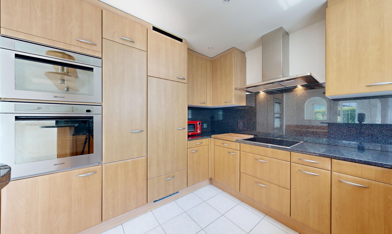 cuisine avec armoires marron clair, light brown cabinets, four, hotte, et light floor