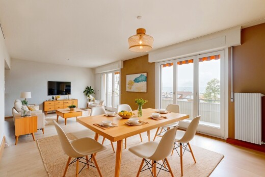 wohn- / esszimmer mit fernseher, gipskartonwand, natürliches licht, holzfußboden, und kühler