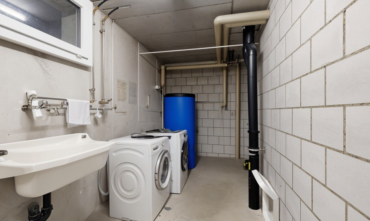 buanderie avec inside property, chauffe-eau, buanderie, sol en béton, et concrete floor