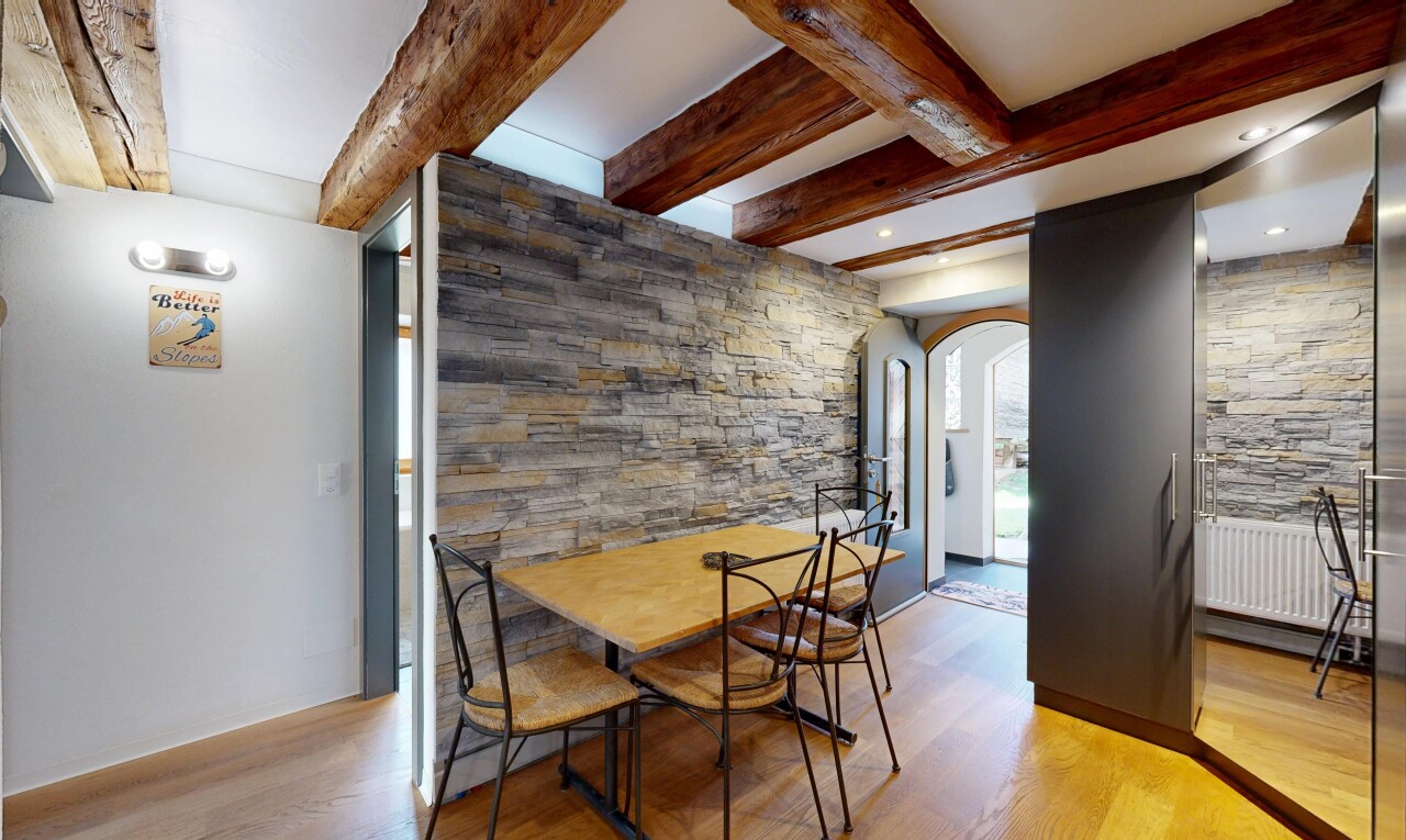 salle à manger avec passages en arc, stone wall, mur en pierre, beamed ceiling, et plafond à poutres