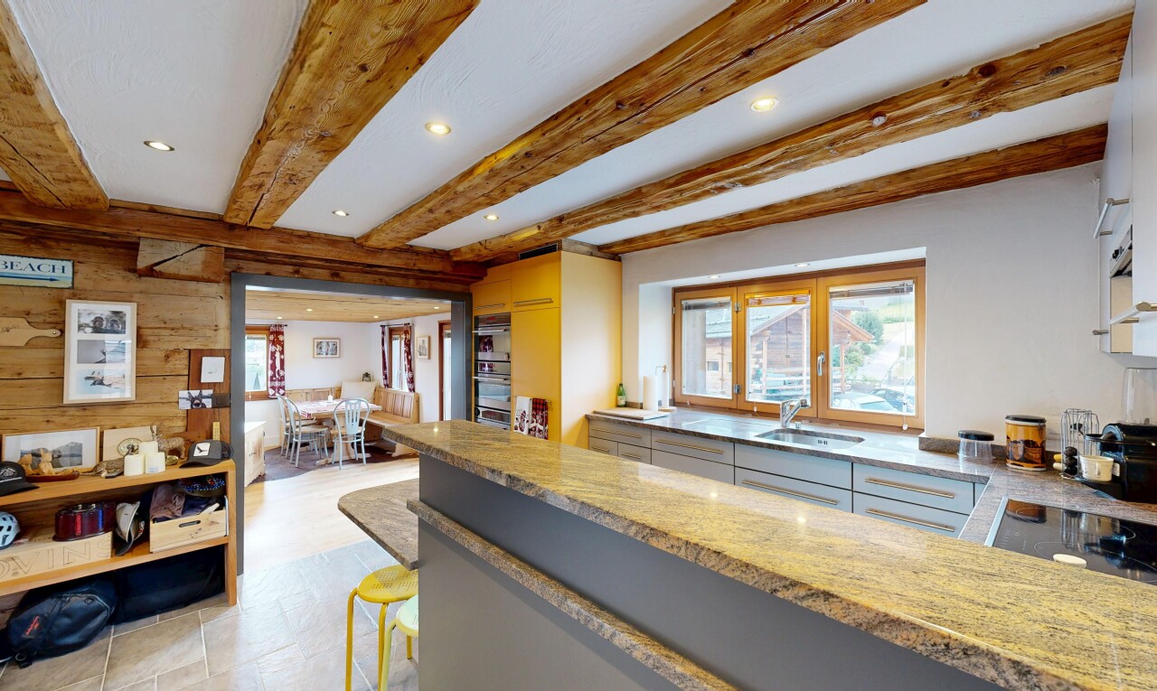 cuisine avec éclairage encastré, beamed ceiling, light floor, stone countertops, et plans de travail en pierre