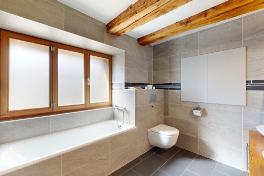 full bath with tile walls, beamed ceiling, a garden tub, dark tile patterned flooring, and vanity