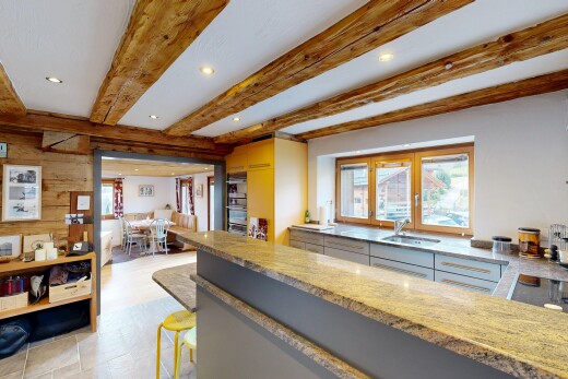 kitchen with recessed lighting, beamed ceiling, light stone countertops, a breakfast bar area, and a peninsula
