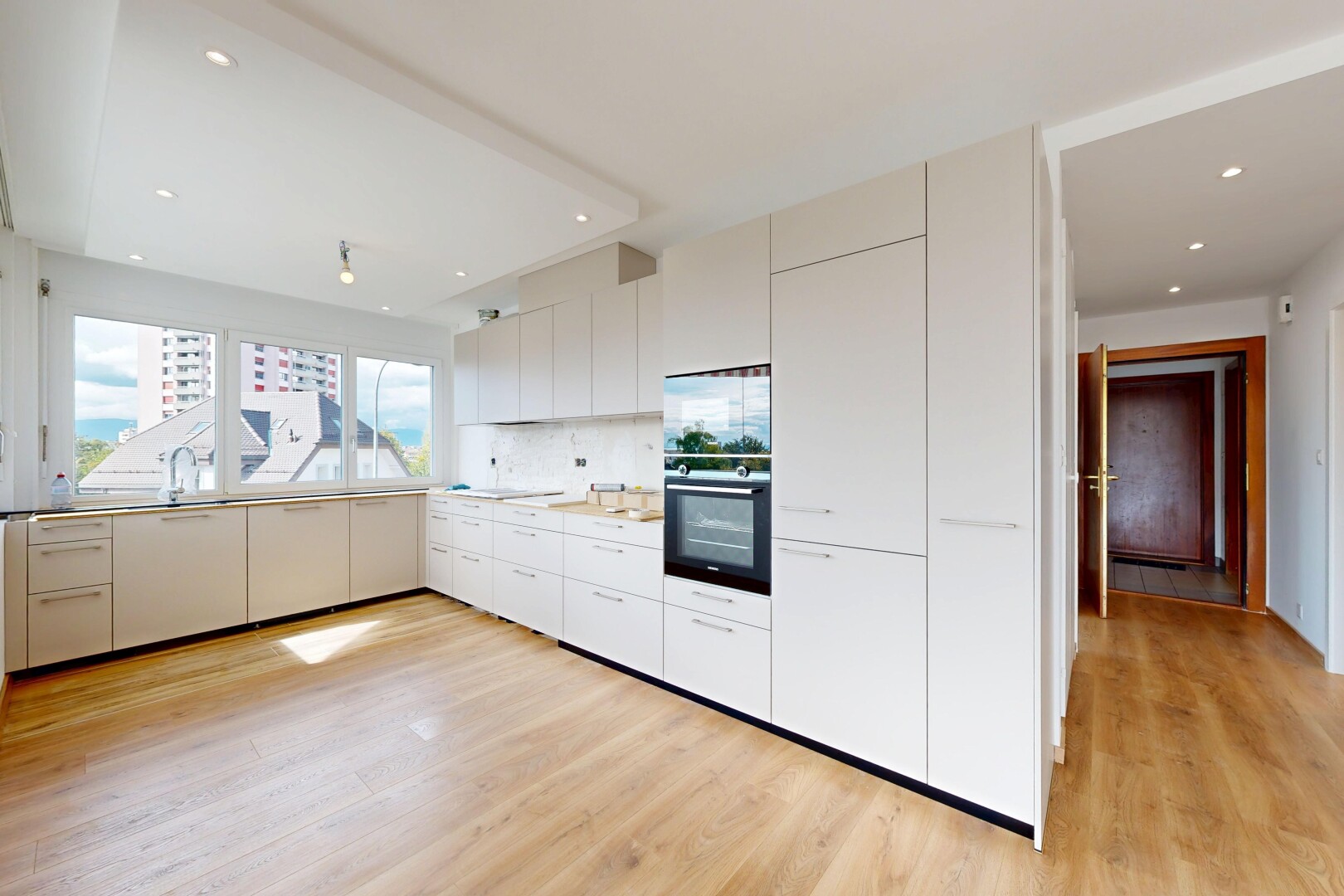 kitchen with modern cabinets, black oven, white cabinetry, light wood-type flooring, and light countertops