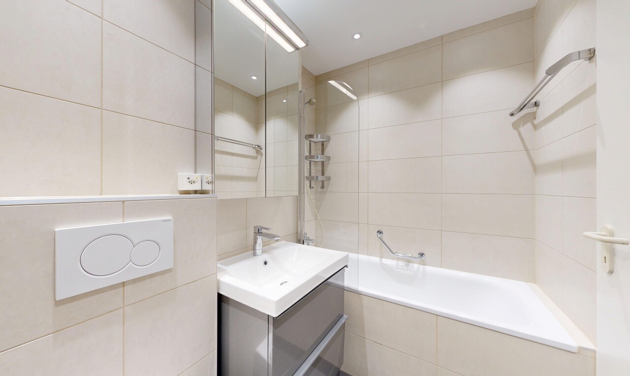 full bath featuring tile walls, tiled shower / bath combo, and vanity