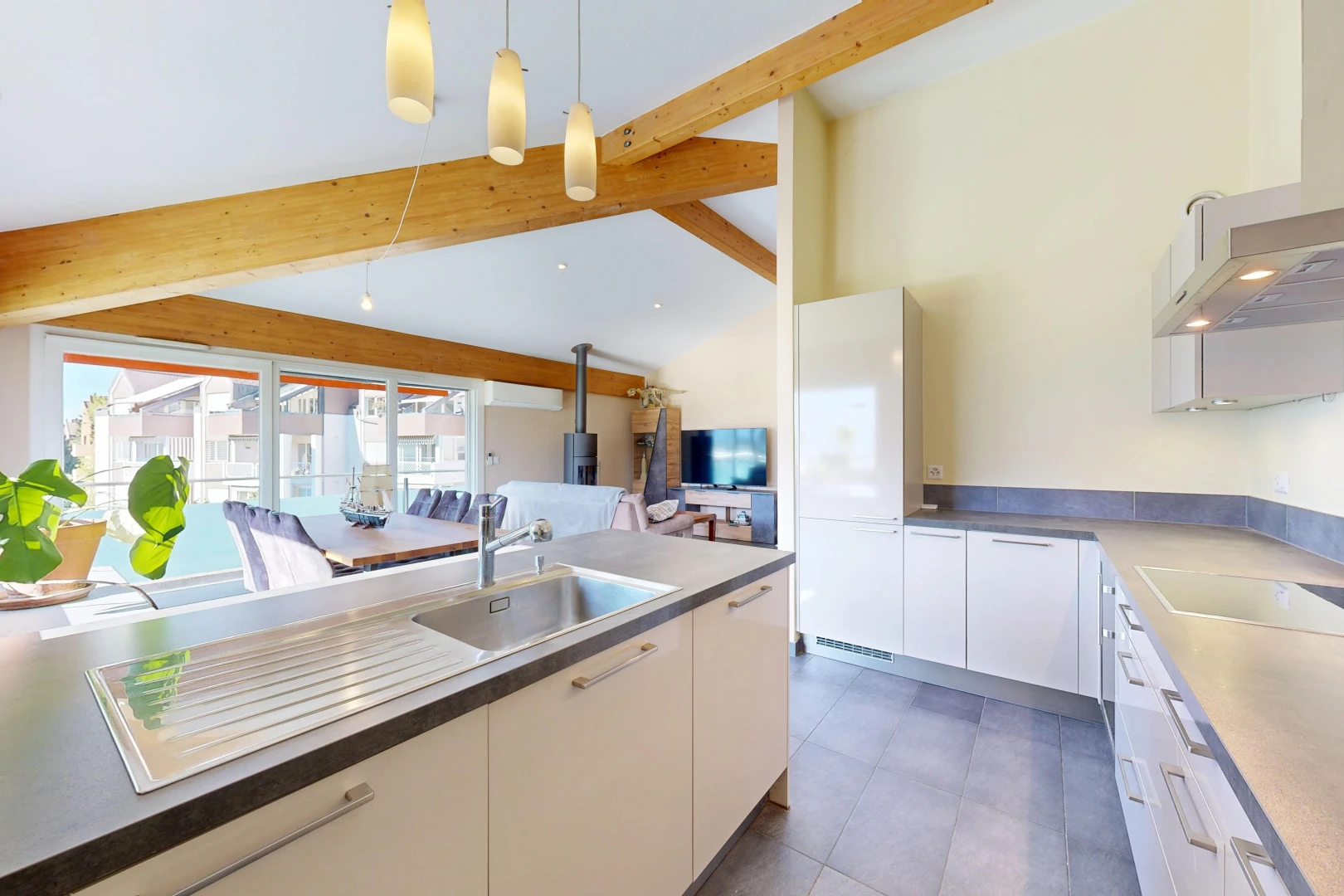cuisine avec hotte, évier, télévision, high end ceiling, et éclairage suspendu