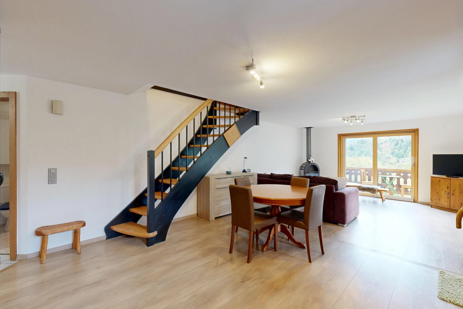 salon / salle à manger avec poêle à bois, escaliers, cloison sèche, drywall, et wood finish stairs