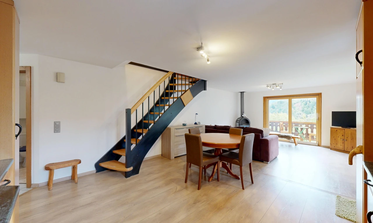 salon / salle à manger avec poêle à bois, escaliers, cloison sèche, drywall, et wood finish stairs