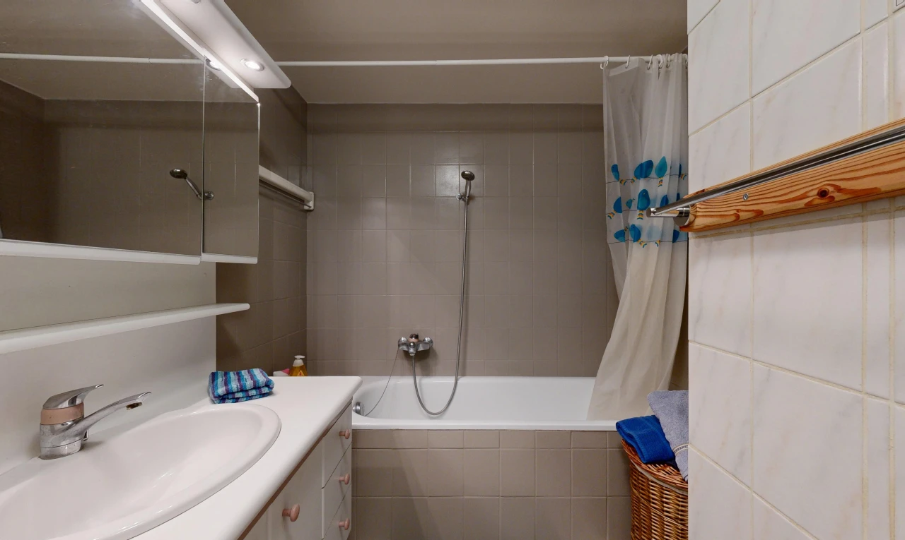 salle de bains avec lavabo (ou coiffeuse selon le contexte), évier, salle de bain complète, douche-bain combinés, et miroir
