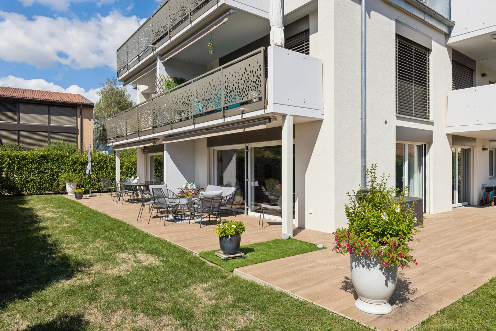 façade avec balcon, terrasse, pelouse, bardage en stuc, et day time