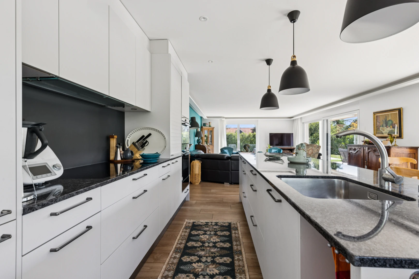cuisine avec éclairage suspendu, évier, dark countertops, armoires blanches, et white cabinets