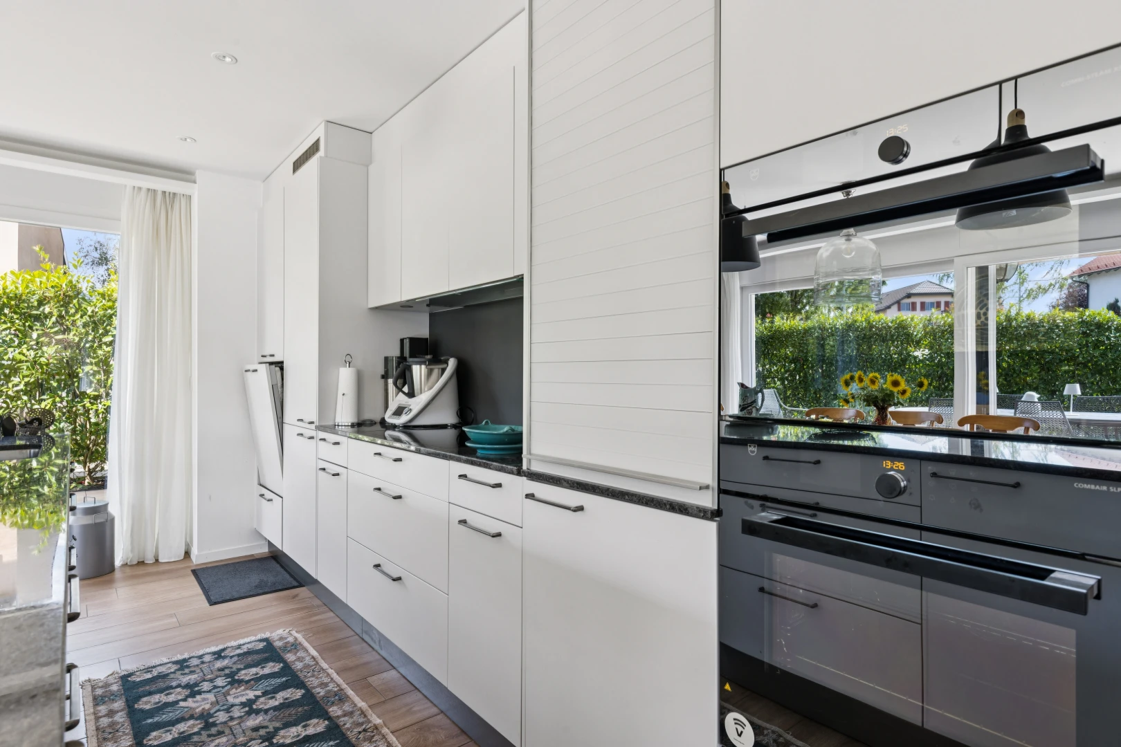 cuisine avec dark countertops, armoires blanches, white cabinets, sol en finition bois, et wood finish floor