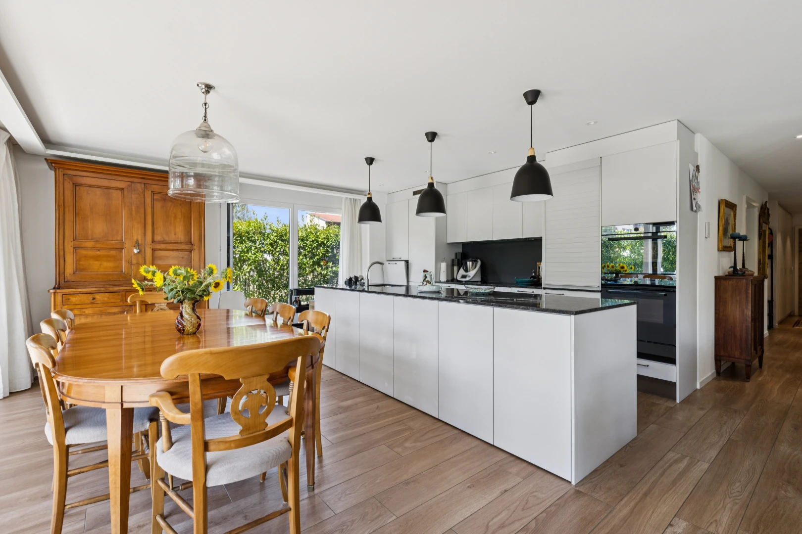 cuisine avec éclairage suspendu, dark countertops, plans de travail, four double, et wood finish floor