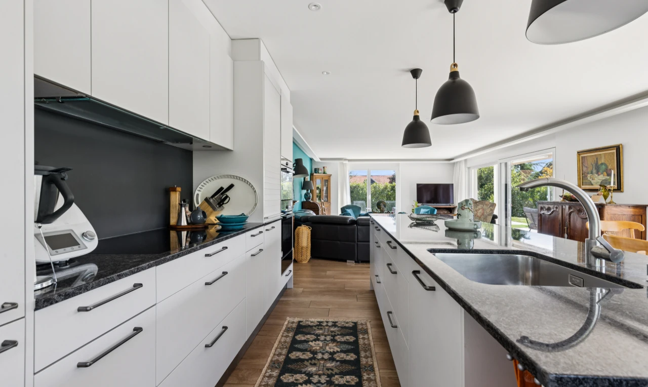 cuisine avec éclairage suspendu, évier, dark countertops, armoires blanches, et white cabinets
