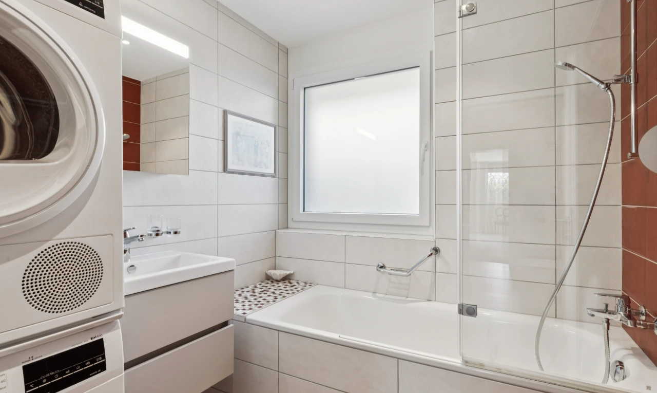 salle de bains avec lavabo (ou coiffeuse selon le contexte), douche-bain combinés, miroir, salle de bain complète, et tile wall