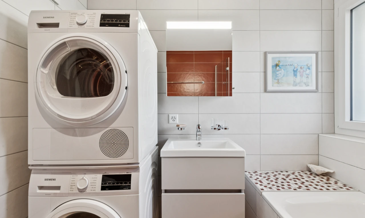 buanderie avec lave-linge et sèche-linge superposés, évier, inside property, tile wall, et mur en carrelage