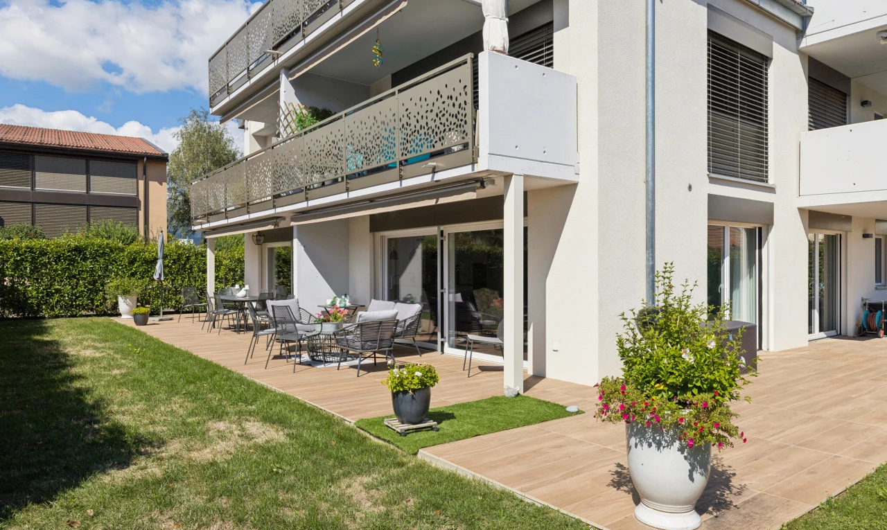 façade avec balcon, terrasse, pelouse, bardage en stuc, et day time