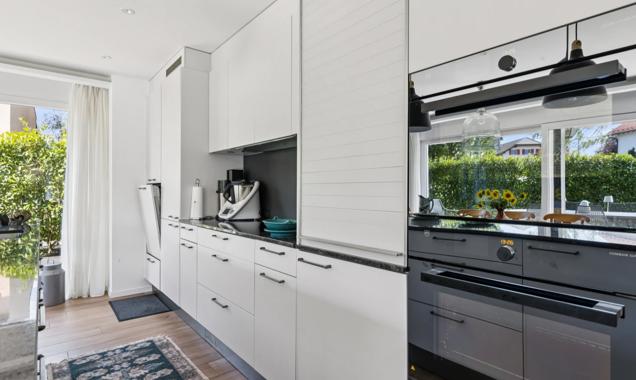 cuisine avec dark countertops, armoires blanches, white cabinets, sol en finition bois, et wood finish floor