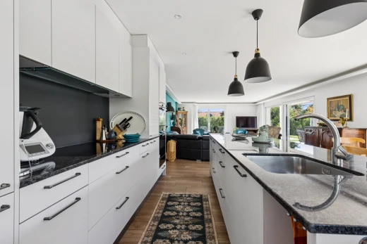 cuisine avec éclairage suspendu, évier, dark countertops, armoires blanches, et white cabinets