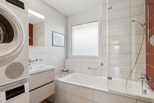 salle de bains avec lavabo (ou coiffeuse selon le contexte), douche-bain combinés, miroir, salle de bain complète, et tile wall