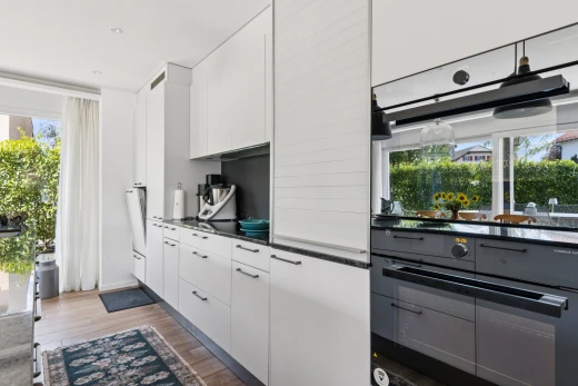 cuisine avec dark countertops, armoires blanches, white cabinets, sol en finition bois, et wood finish floor