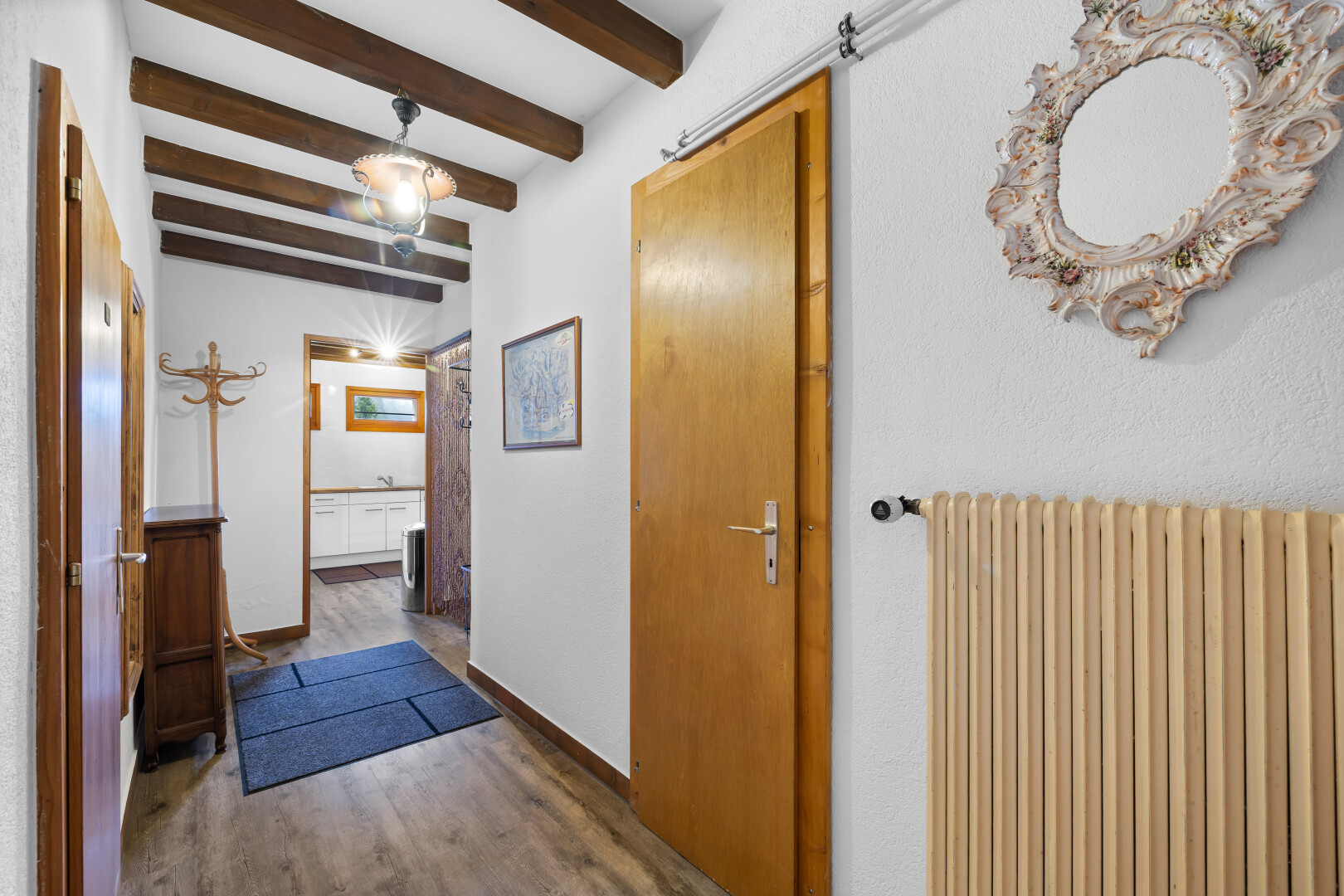 couloir avec radiateur, plafond à poutres, beamed ceiling, inside property, et sol en finition bois