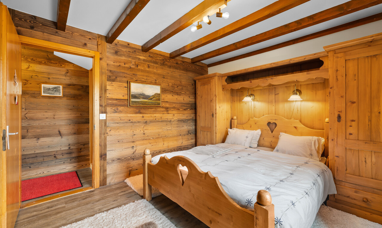 chambre avec mur en bois, wood wall, inside property, plafond à poutres, et beamed ceiling