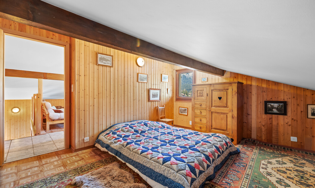 chambre avec beamed ceiling, plafond à poutres, parquet floor, wood wall, et mur en bois