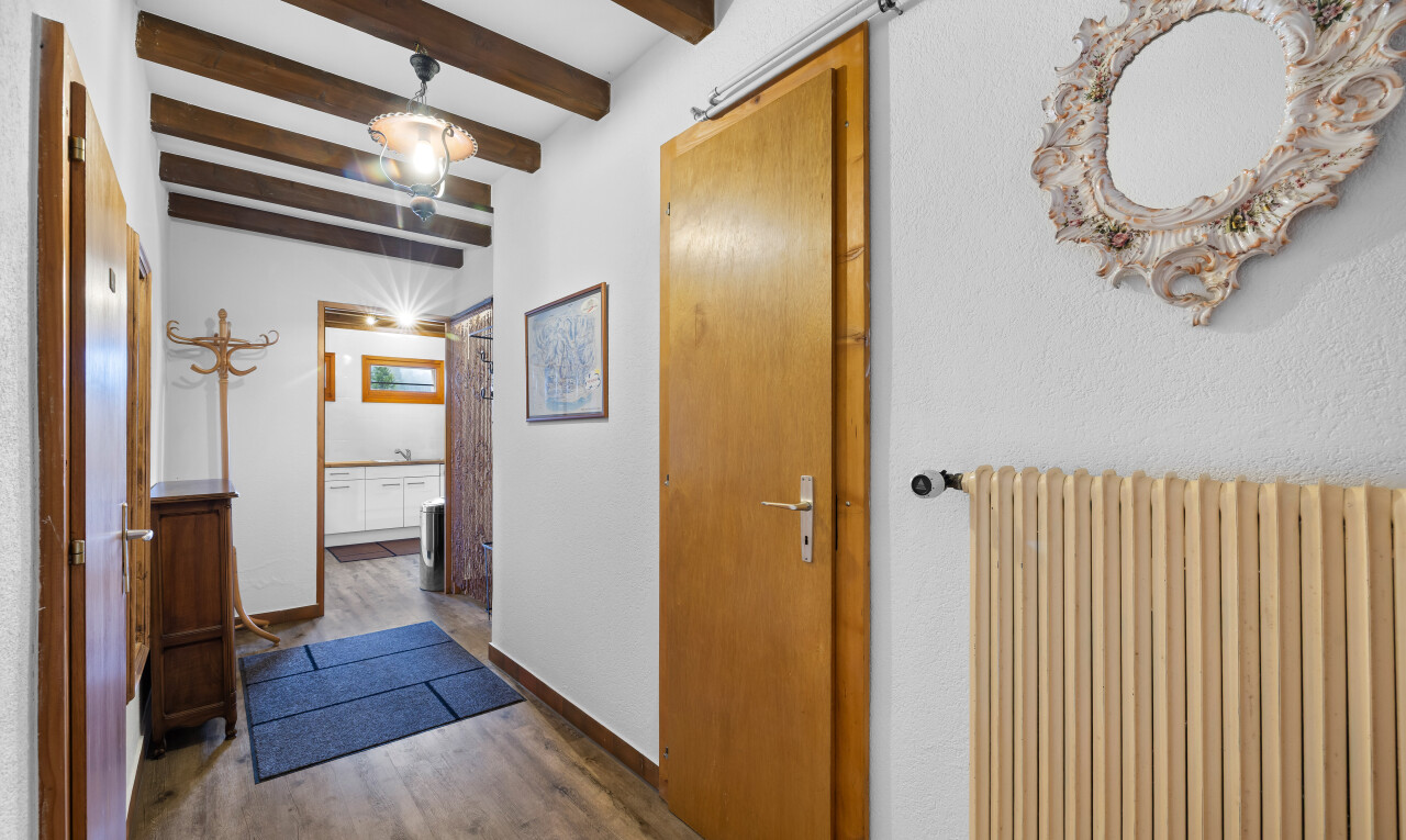 couloir avec radiateur, plafond à poutres, beamed ceiling, inside property, et sol en finition bois