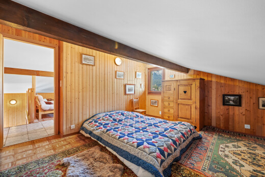 chambre avec beamed ceiling, plafond à poutres, parquet floor, wood wall, et mur en bois