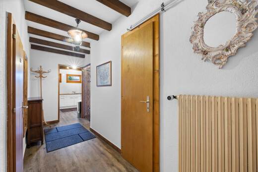 couloir avec radiateur, plafond à poutres, beamed ceiling, inside property, et sol en finition bois