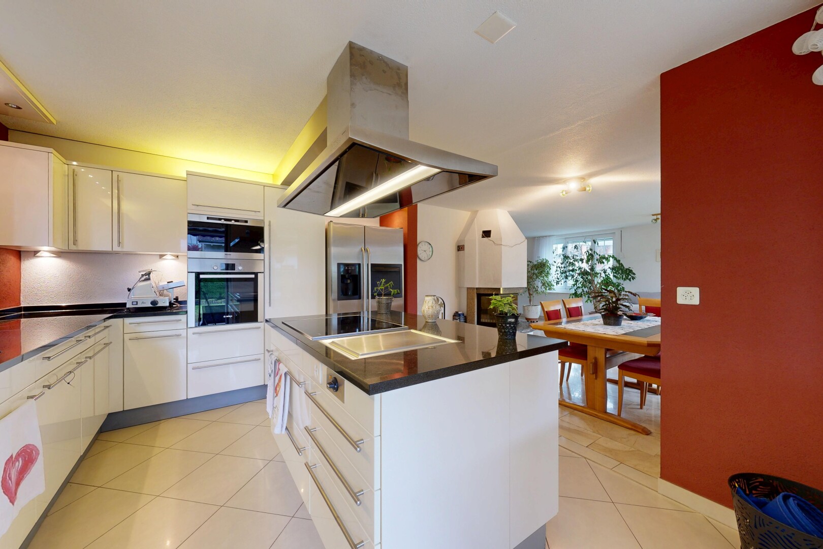 cuisine avec hotte, sol en carrelage, tile floor, îlot de cuisine, et lumière naturelle