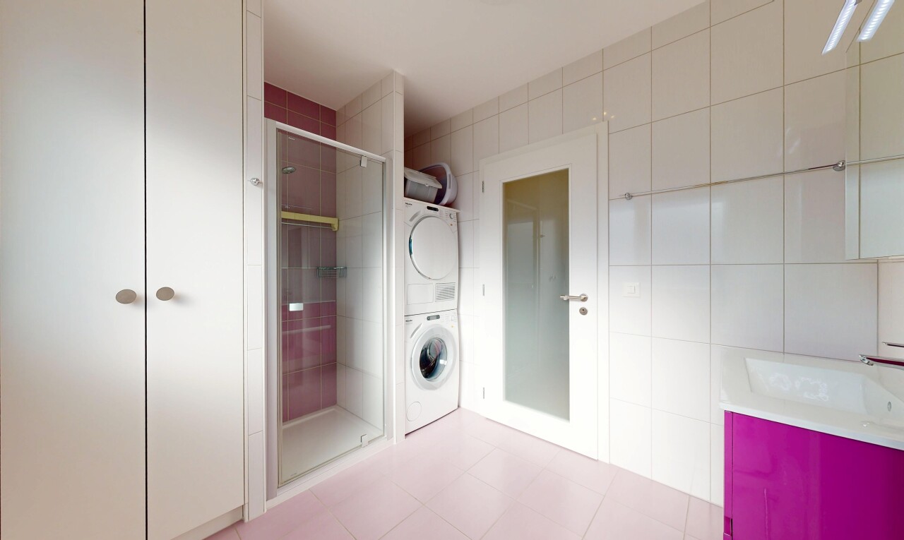 salle de bains avec light floor, salle de bain complète, lave-linge et sèche-linge superposés, mur en carrelage, et tile wall