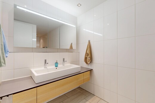 salle de bains avec lavabo (ou coiffeuse selon le contexte), mur en carrelage, tile wall, évier, et light floor