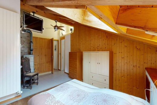 zimmer / schlafzimmer mit holzofen, dachschräge, vaulted ceiling, fernseher, und holzwand