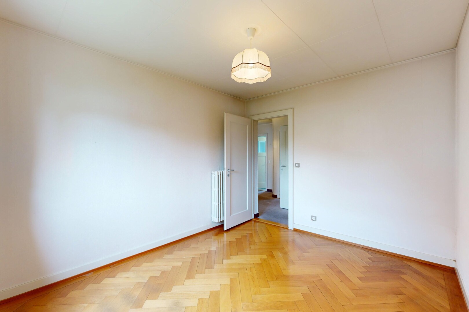 empty room with parquet floors and radiator heating unit
