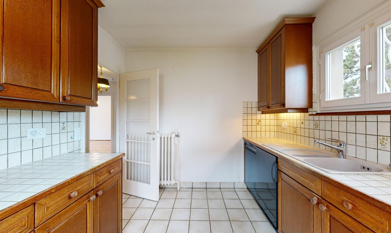 kitchen featuring tasteful backsplash, tile counters, wood finish cabinetry, black dishwasher, and radiator