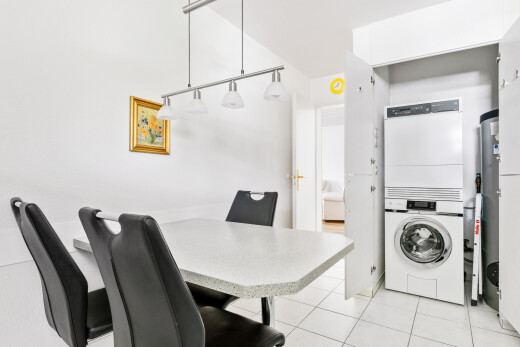 salle à manger avec light floor, lave-linge et sèche-linge superposés, drywall, cloison sèche, et inside property