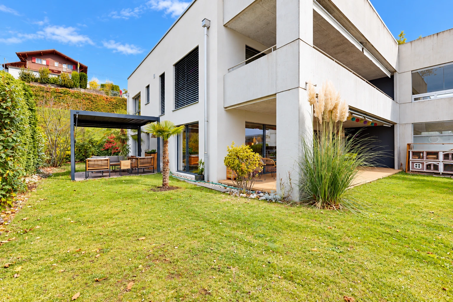 outdoor house with a balcony, a patio, a lawn, and stucco siding