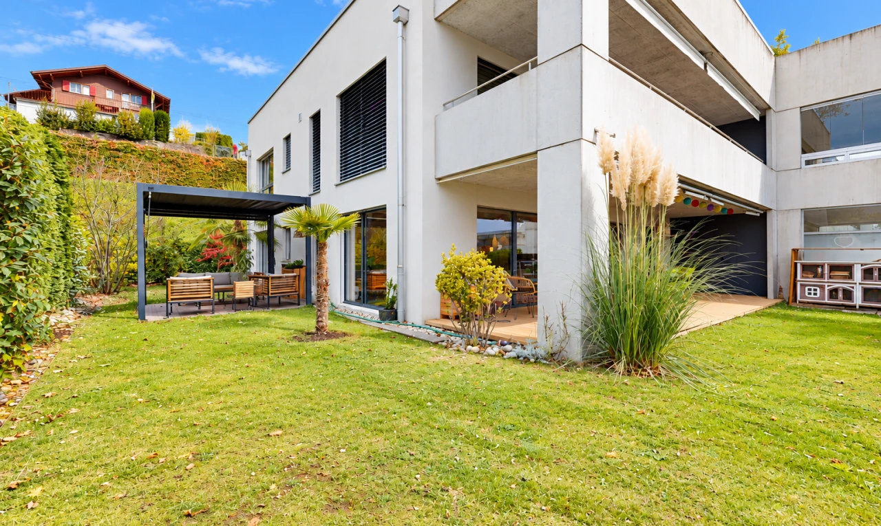 outdoor house with a balcony, a patio, a lawn, and stucco siding