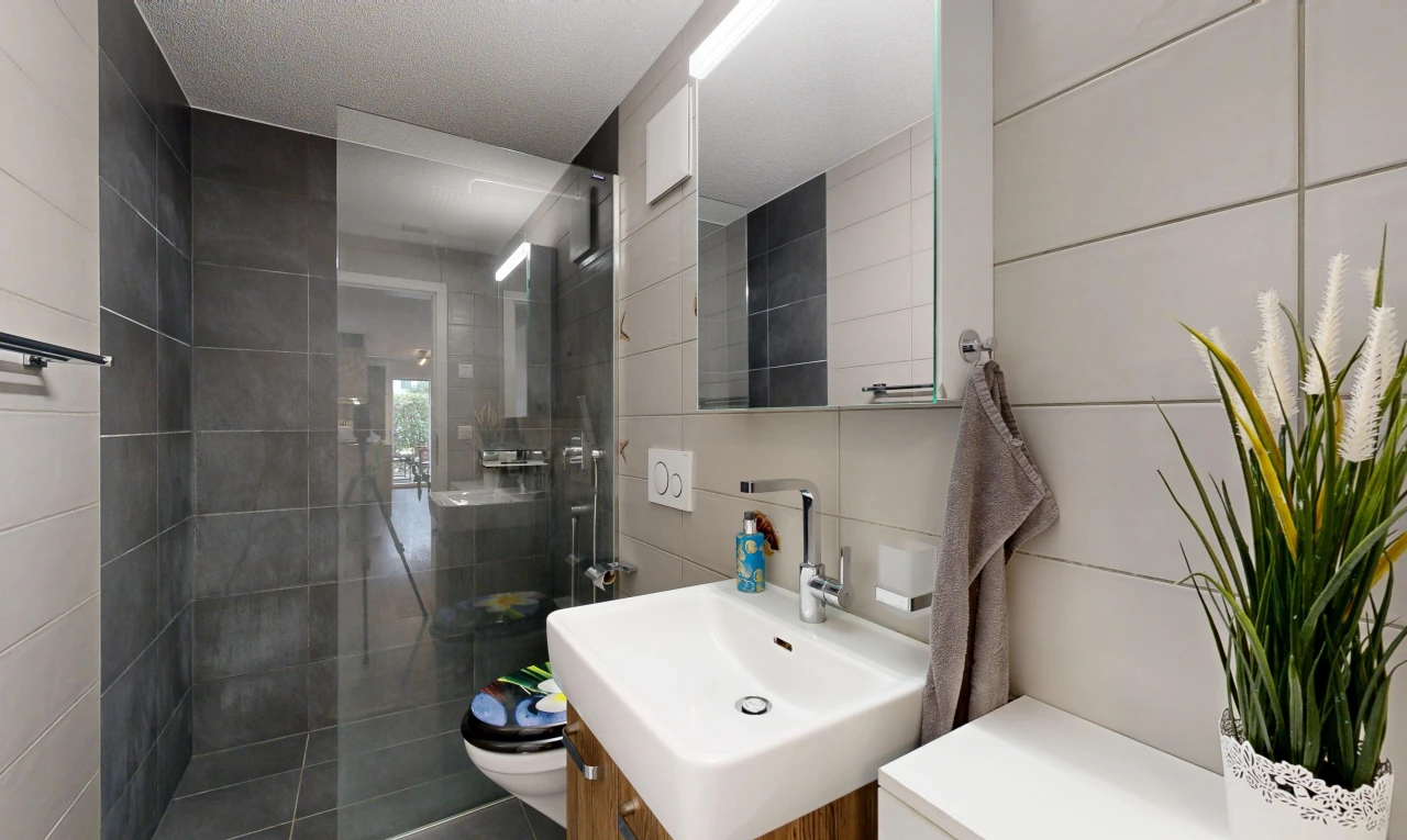 bathroom featuring a tile shower, vanity, and tile walls