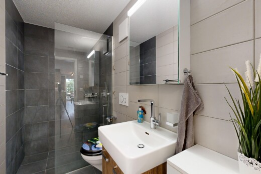 bathroom featuring a tile shower, vanity, and tile walls