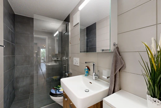 bathroom featuring a tile shower, vanity, and tile walls
