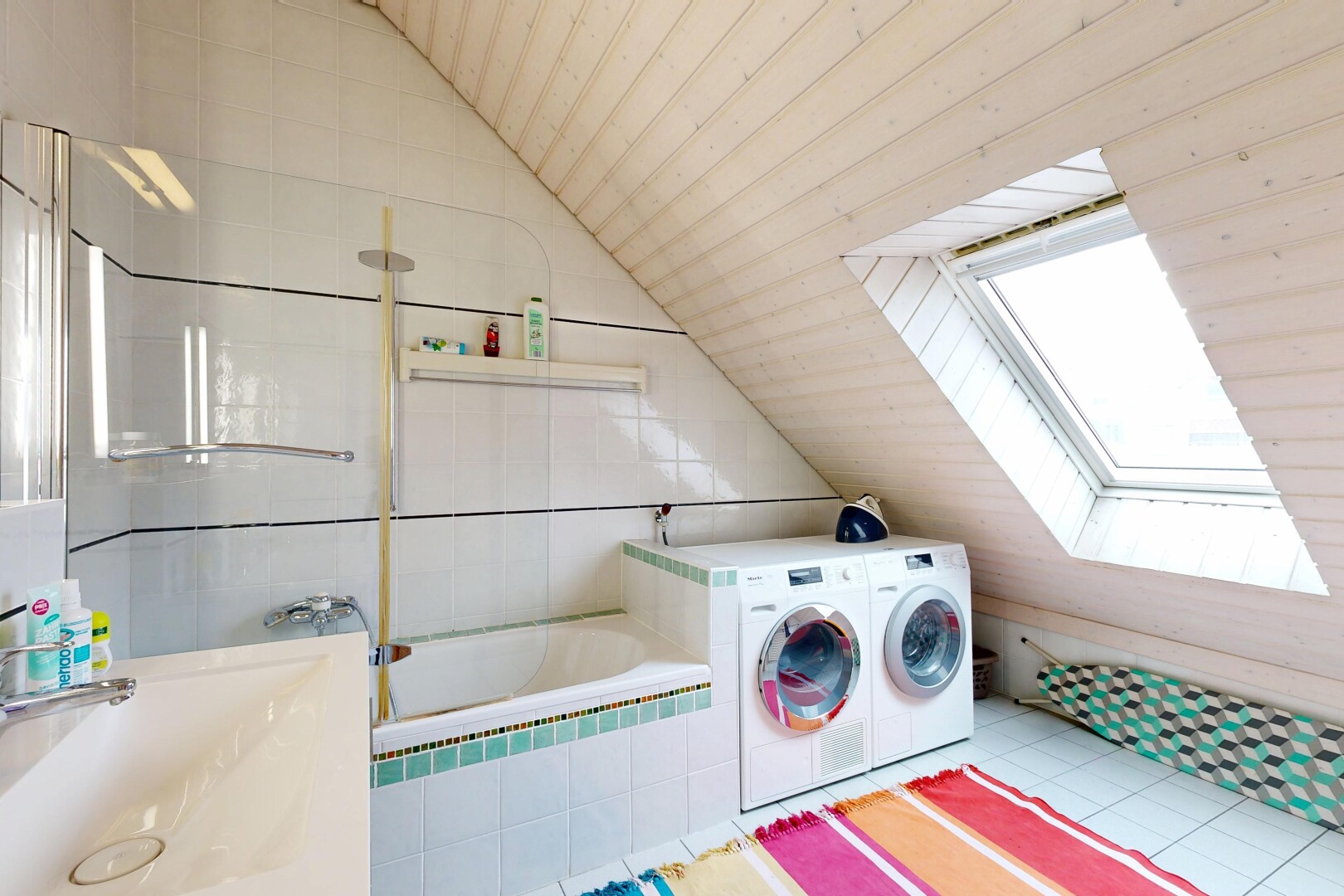 laundry area with washer / clothes dryer, vaulted ceiling, a skylight, and light tile patterned floors