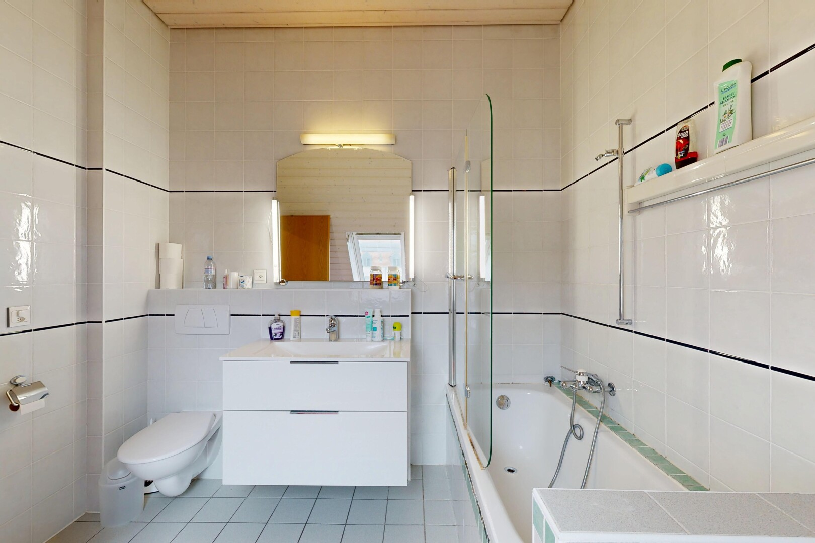 bathroom featuring tile walls, tiled shower / bath combo, light tile patterned floors, and vanity