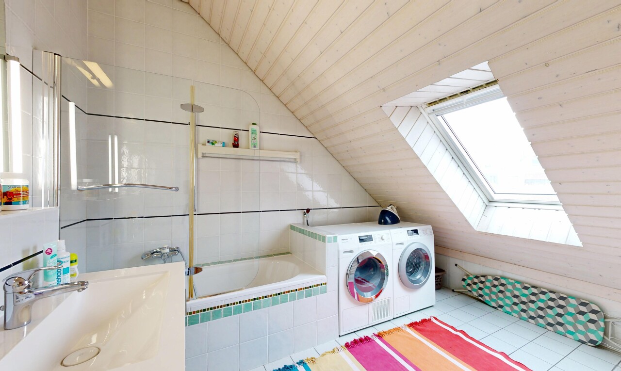 laundry area with washer / clothes dryer, vaulted ceiling, a skylight, and light tile patterned floors
