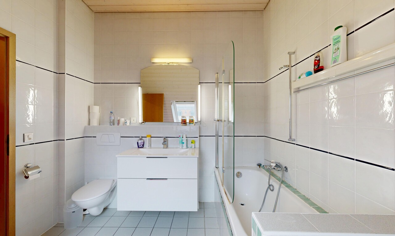 bathroom featuring tile walls, tiled shower / bath combo, light tile patterned floors, and vanity