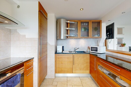 cuisine avec plans de travail en pierre, stone countertops, dark countertops, armoires avec insert en verre, et glass insert cabinets
